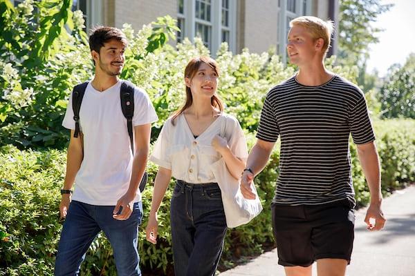 Students walk along the sidewalk next to B.B Comer Hall